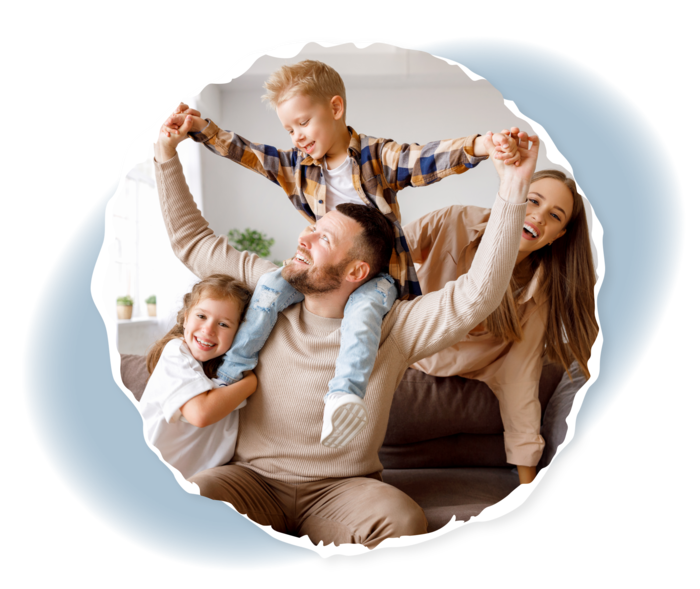 Alltag mit einer chronischen Blutkrankheit: Familienplanung Eine Frau, ein Mann und zwei Kinder sitzen auf einem Sofa und lachen.