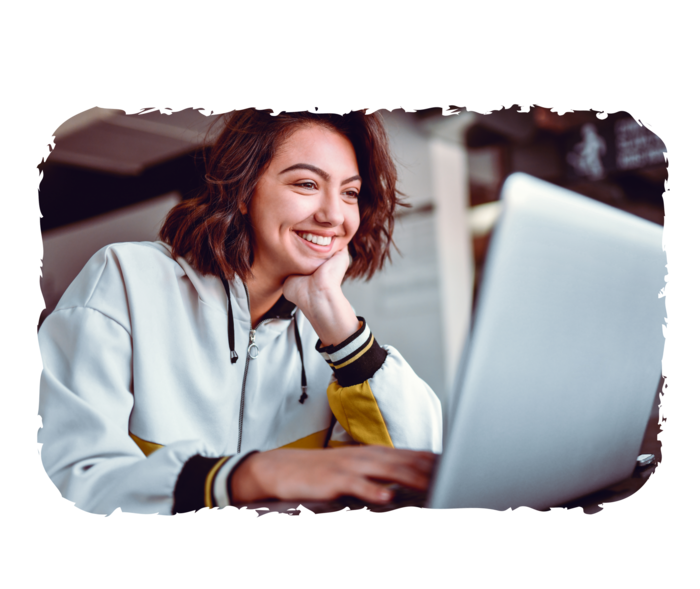 Eine Frau schaut lächelnd auf einen Laptop.