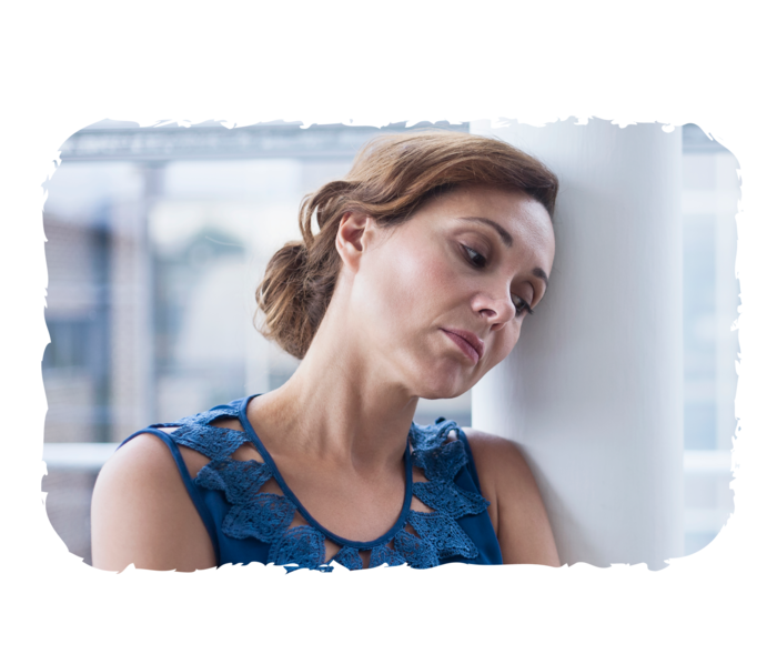 Eine Frau lehnt ihren Kopf gegen eine Wand und sieht müde aus. 