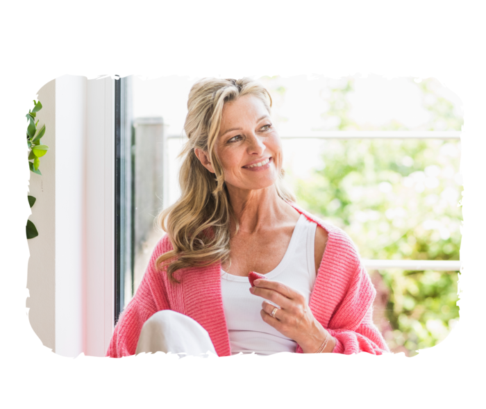 Eine ältere Frau lächelt und hält eine Erdbeere in der Hand.  