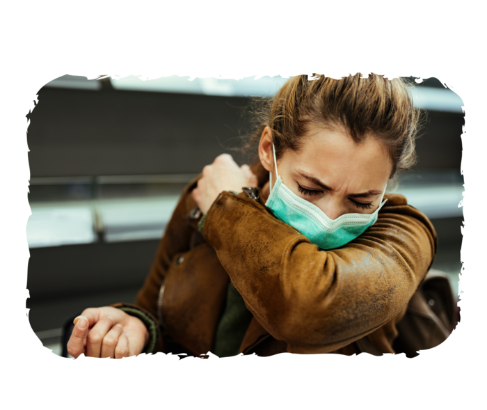 Eine Frau trägt einen Mundschutz und niest in ihre Ellenbeuge.