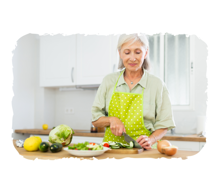 Eine ältere Frau schneidet Gemüse.