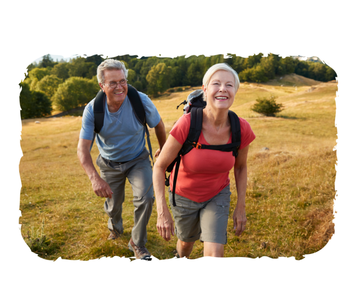 Ein älterer Mann und eine ältere Frau stehen auf einem Hügel und lachen.