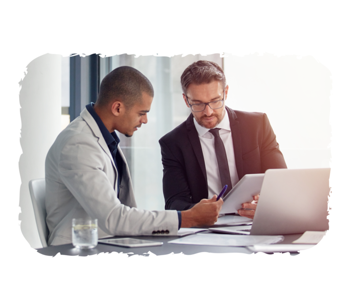 Zwei Männer sitzen an einem Schreibtisch und schauen gemeinsam auf Unterlagen.