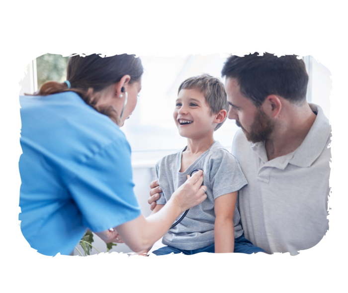 Ein Junge sitzt auf dem Schoß eines Mannes und wird von einer Ärztin mit einem Stethoskop untersucht.