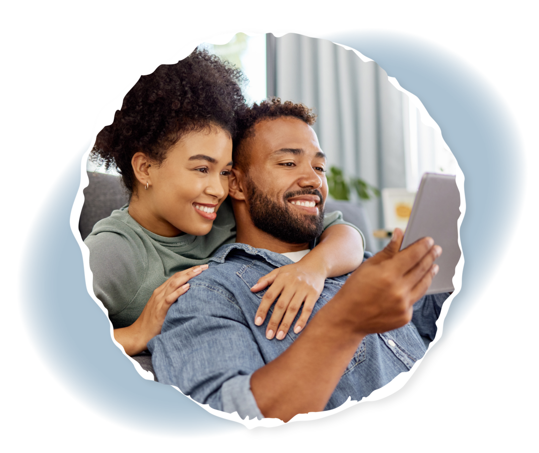 Alltag mit einer chronischen Blutkrankheit: Alltagsroutinen neu ordnen Ein Mann hält einen Tablet-Computer in seiner Hand. Eine Frau umarmt ihn von hinten.