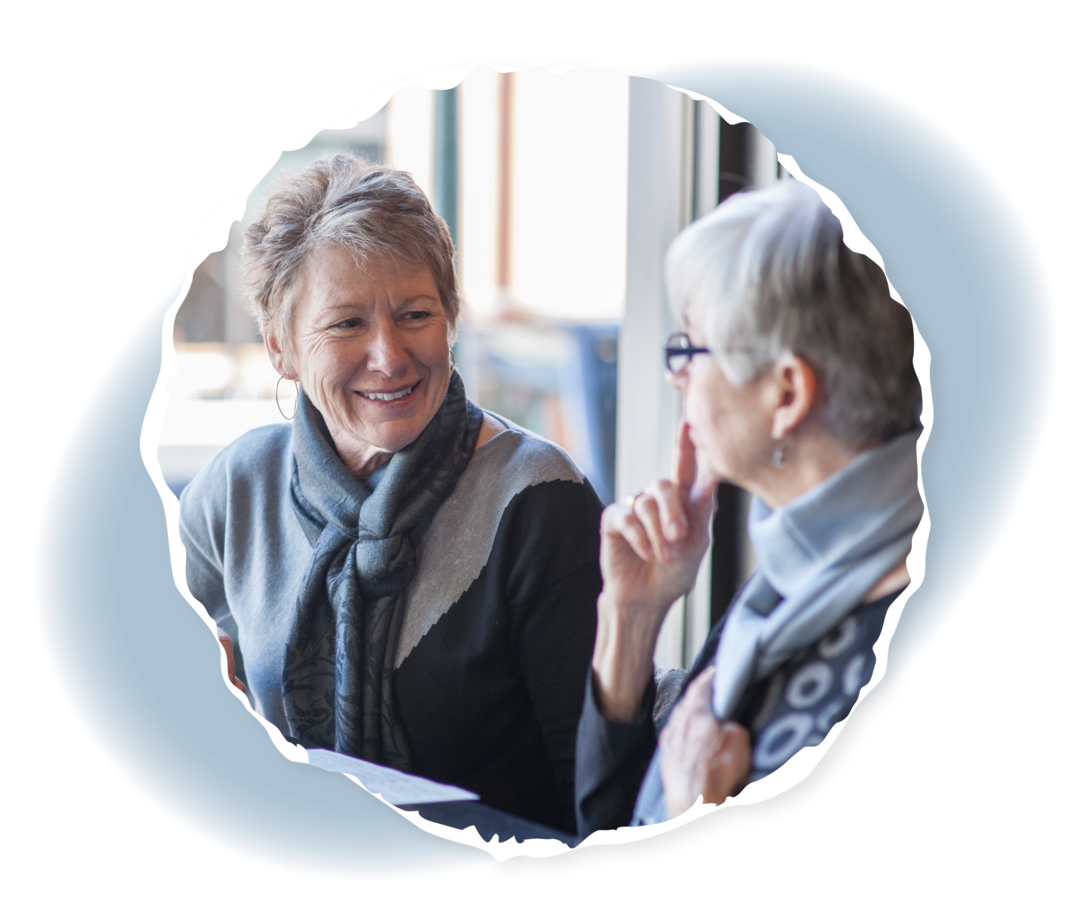 Zwei ältere Frauen sitzen sich gegenüber und schauen sich an.