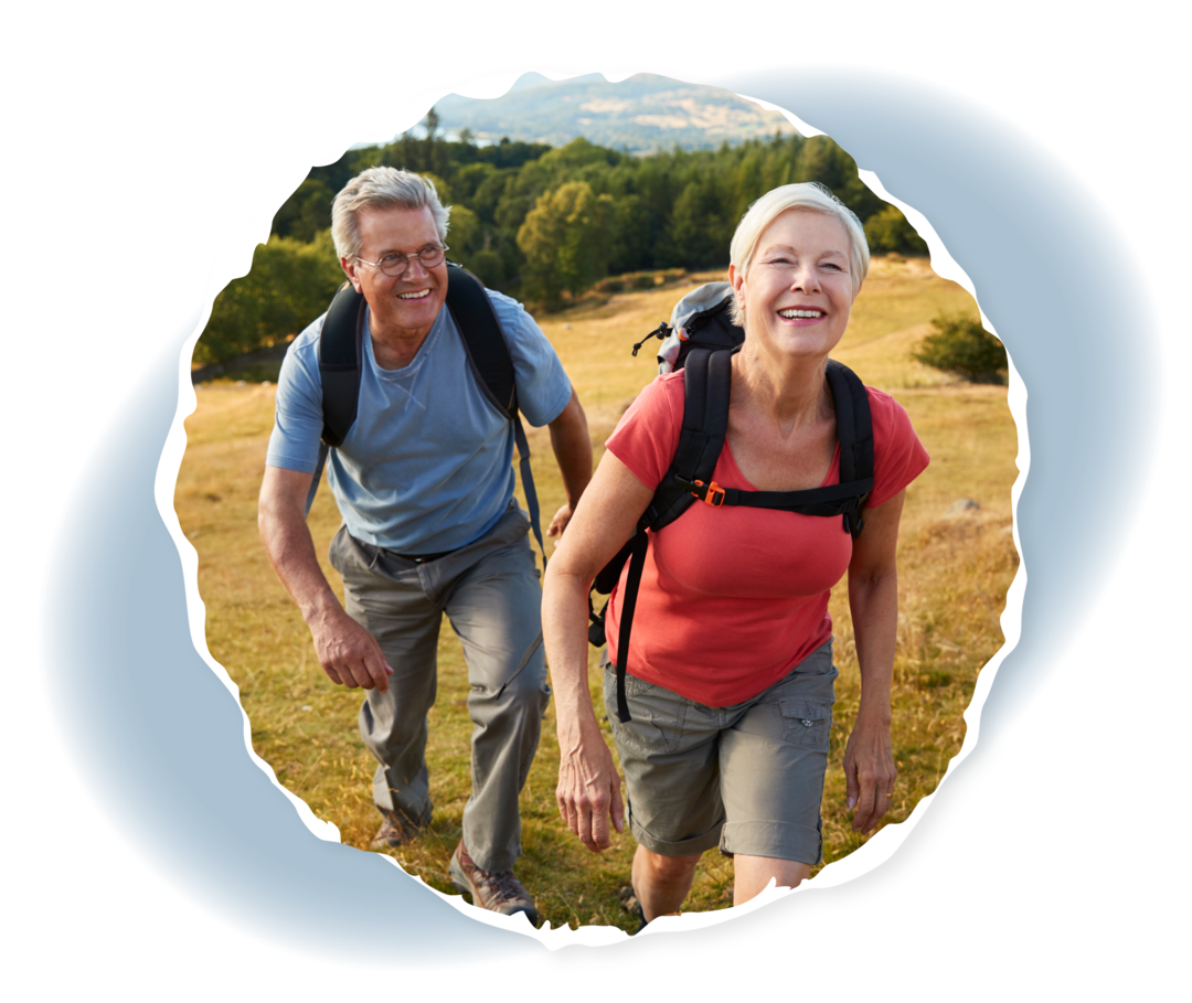 Ein Mann und eine Frau tragen Rucksäcke und laufen einen Hügel hinauf.