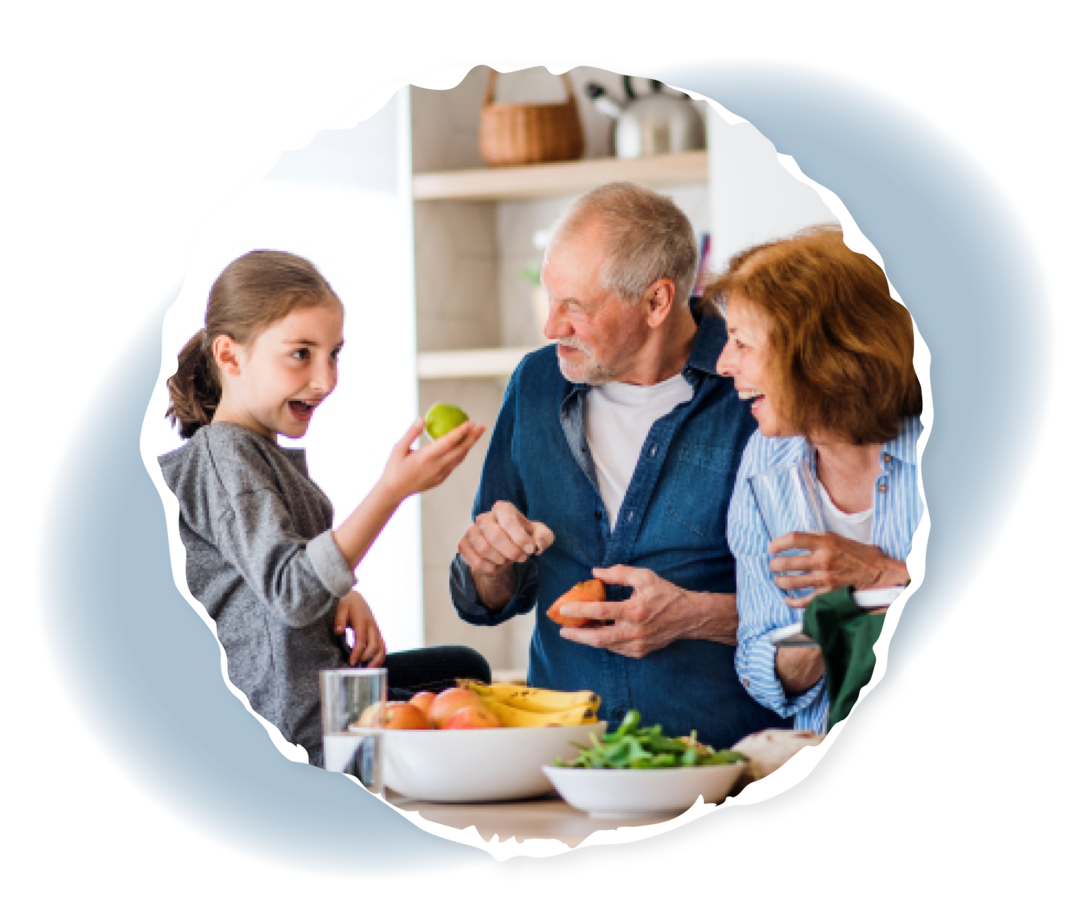 Zwei ältere Menschen und ein Kind an einem Tisch mit Obstschalen.