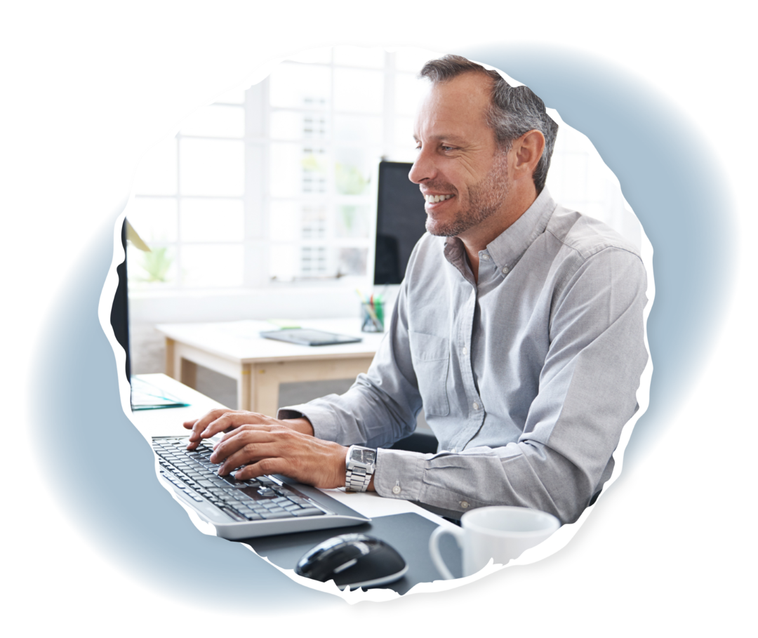 Ein Mann sitzt an einem Schreibtisch und schaut auf einen Computerbildschirm.