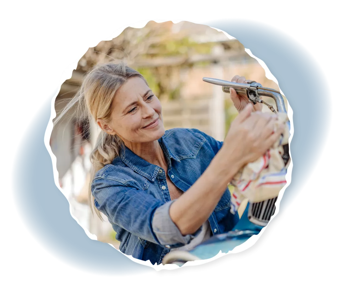 Frau putzt einen Roller mit einem Tuch.