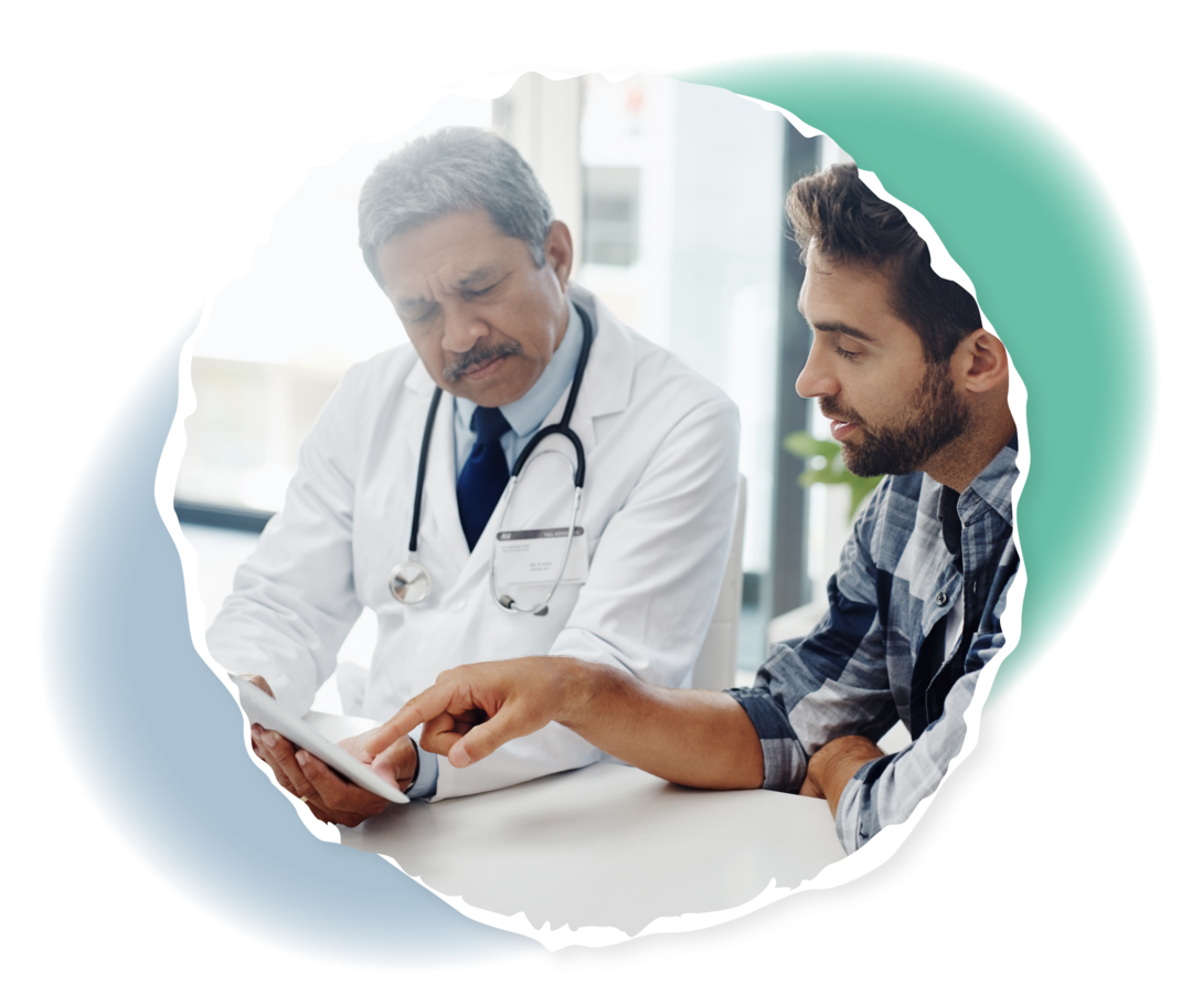 Ein Arzt und ein weiterer Mann sitzen an einem Tisch, beide schauen auf einen Tablet-Computer.