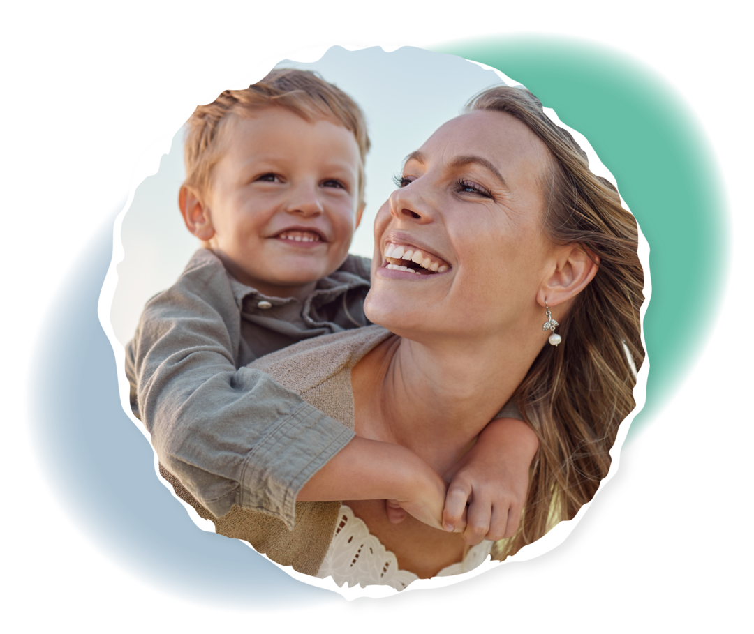 Eine lachende Frau trägt ein Kind auf ihrem Rücken.