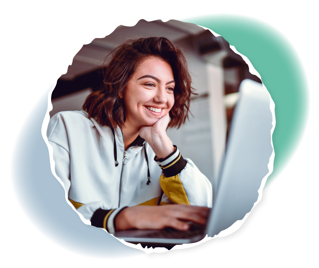 Eine Frau schaut lächelnd auf einen Laptop.