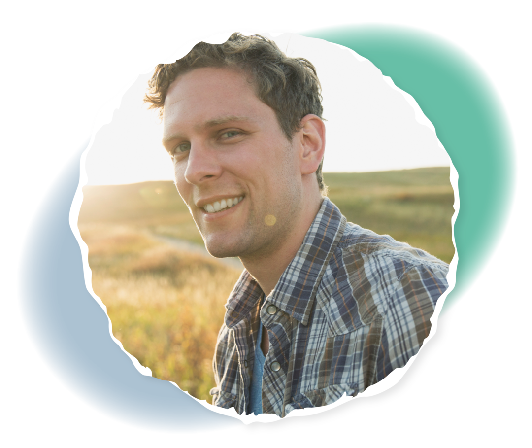 Ein Mann steht vor einem Feld und lächelt in die Kamera.