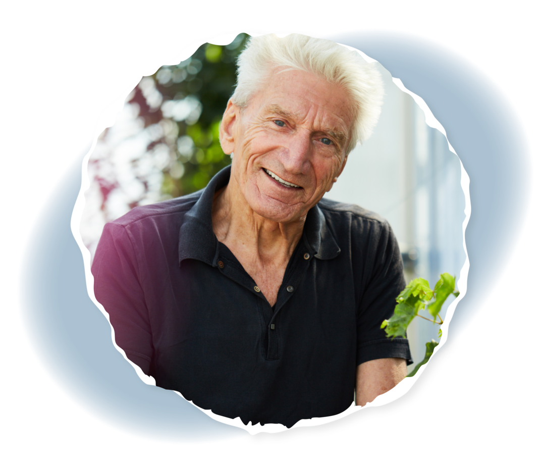 Ein älterer Mann steht draußen vor einer Pflanze.