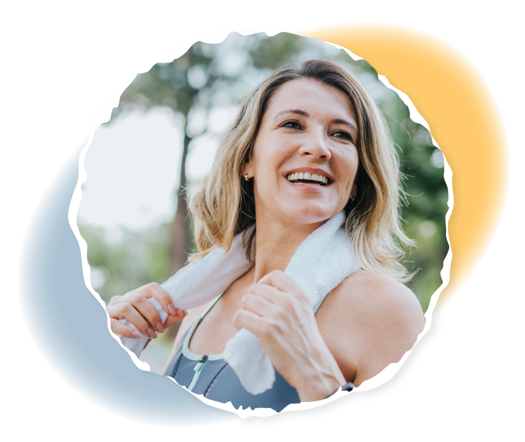 Myelofibrose Eine Frau in Sportkleidung hält ein Handtuch um ihren Hals und lacht.