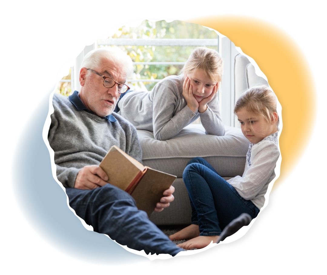 Kurative Therapie: Stammzelltransplantation Ein älterer Mann liest zwei Kindern auf dem Sofa aus einem Buch vor.