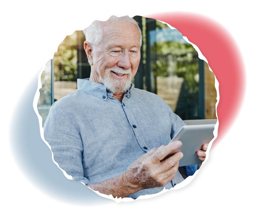 Ein älterer Mann schaut lächelnd auf ein Tablet.