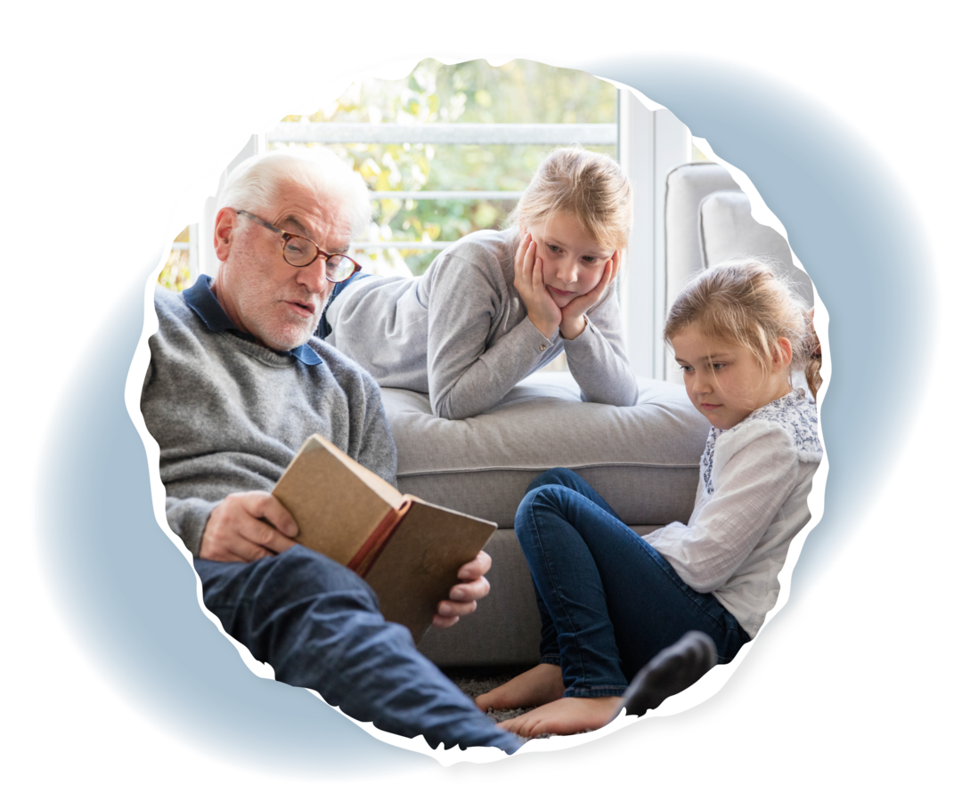 Ein älterer Mann hält ein Buch. Neben ihm zwei Kinder.