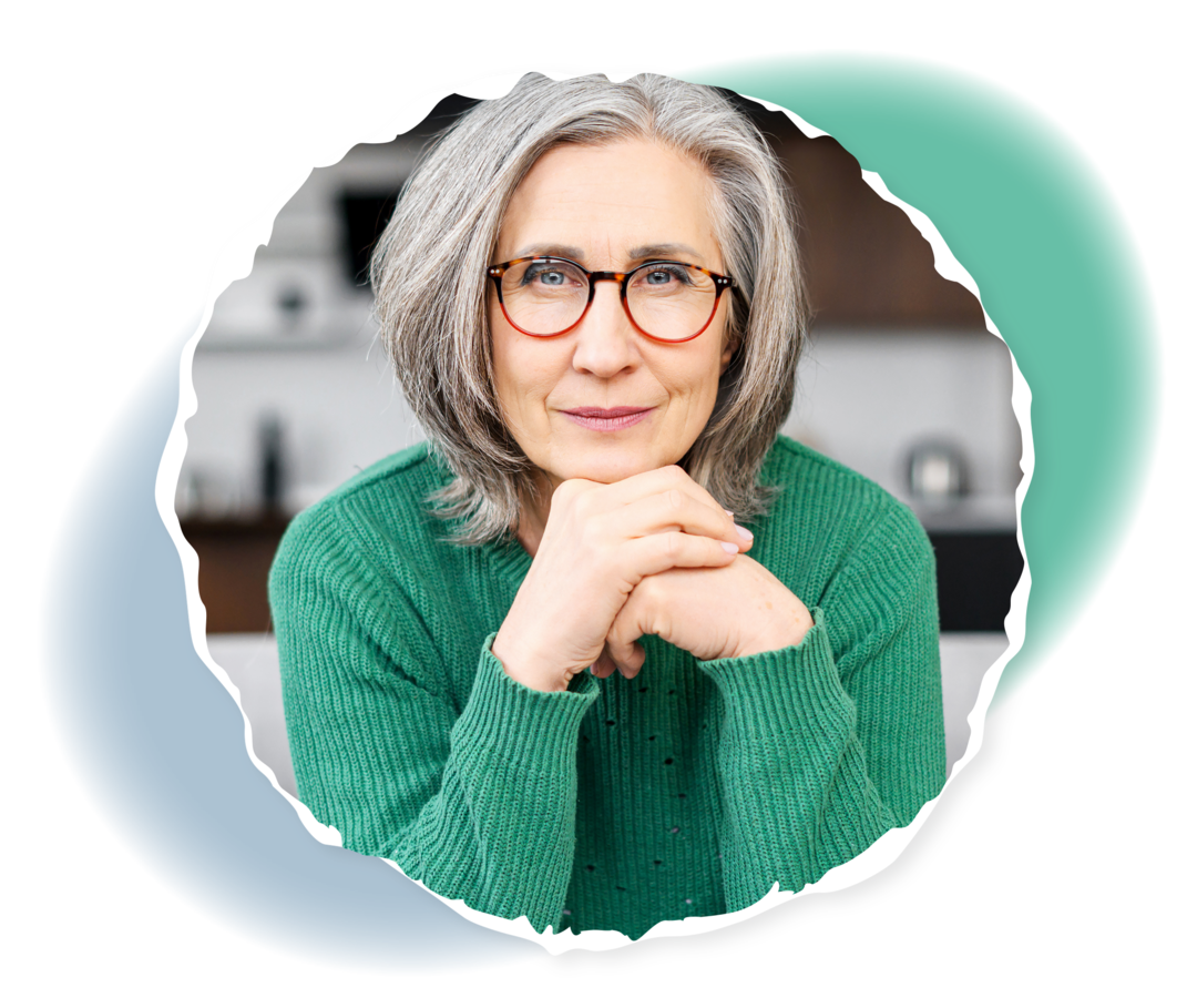 Eine ältere Frau sitzt auf einem Sofa und schaut in die Kamera.