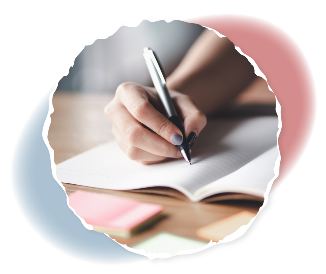 Eine Hand hält einen Stift auf einem aufgeschlagenen Heft. 