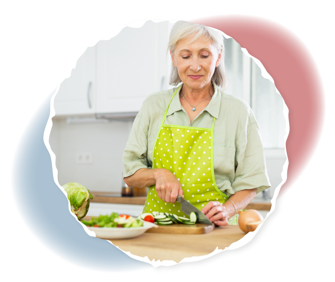 Eine ältere Frau schneidet Gemüse.