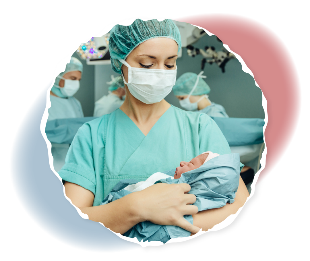 Eine Frau in OP-Kleidung hält ein Neugeborenes auf ihrem Arm. 