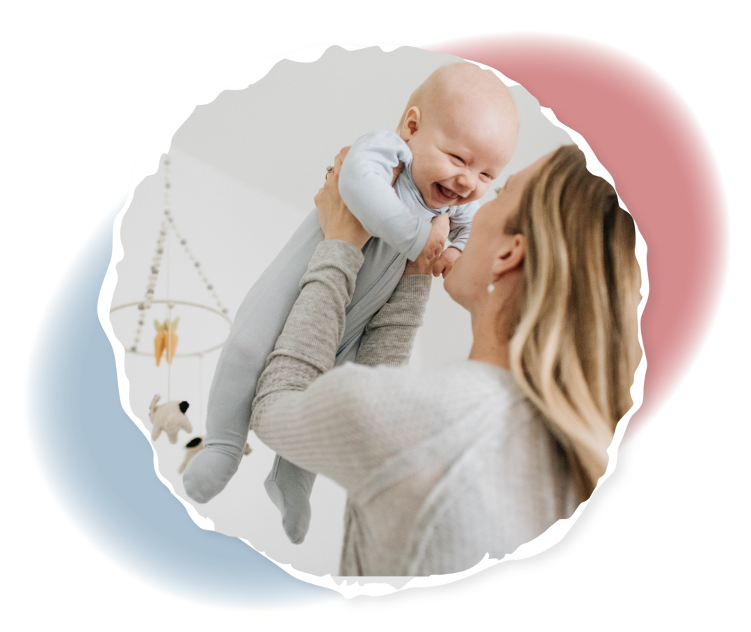 Eine Frau hält einen lachenden Säugling hoch.