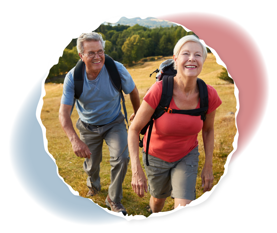 Ein älterer Mann und eine ältere Frau stehen auf einem Hügel und lachen.