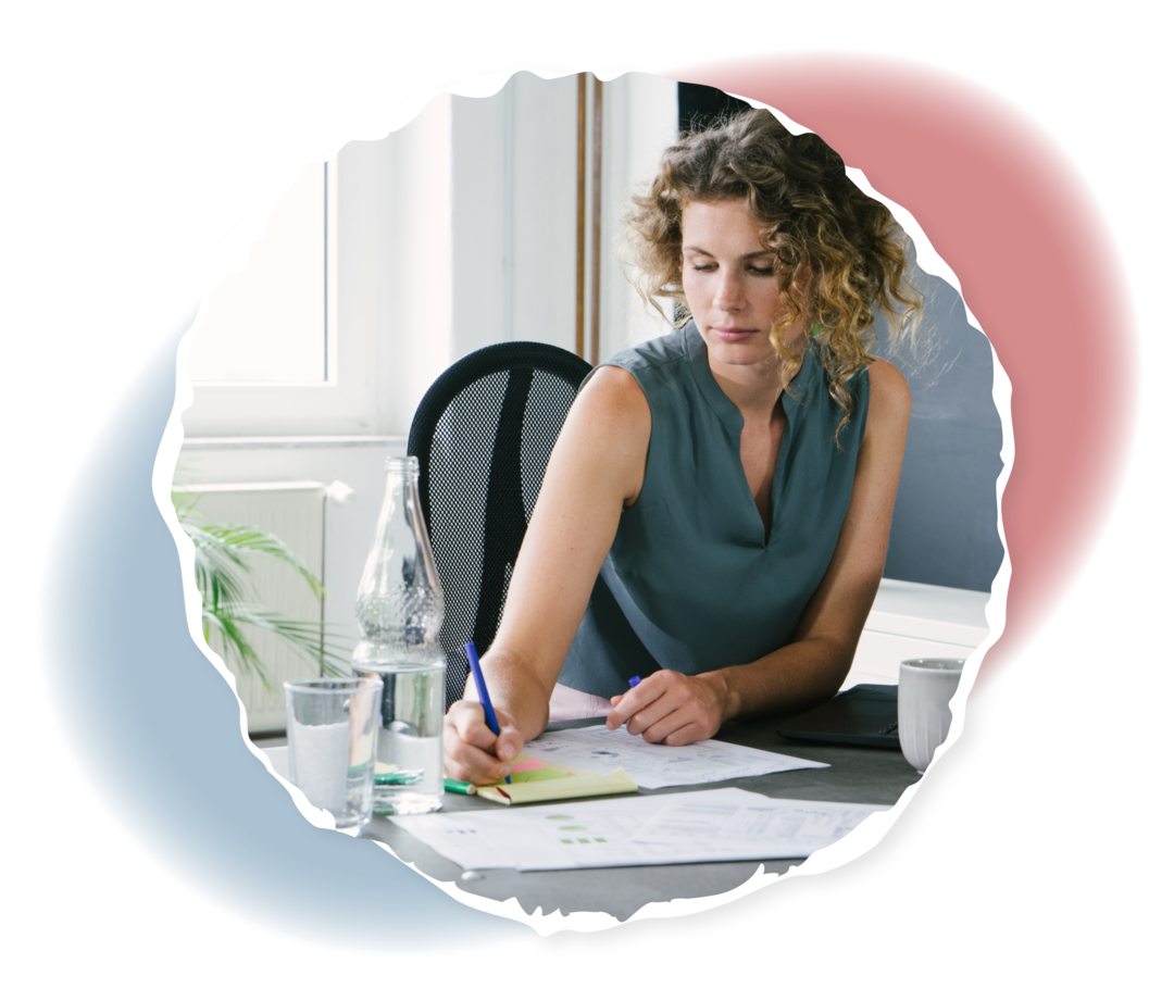 Eine Frau sitzt an einem Schreibtisch und hält einen Stift in ihrer Hand.