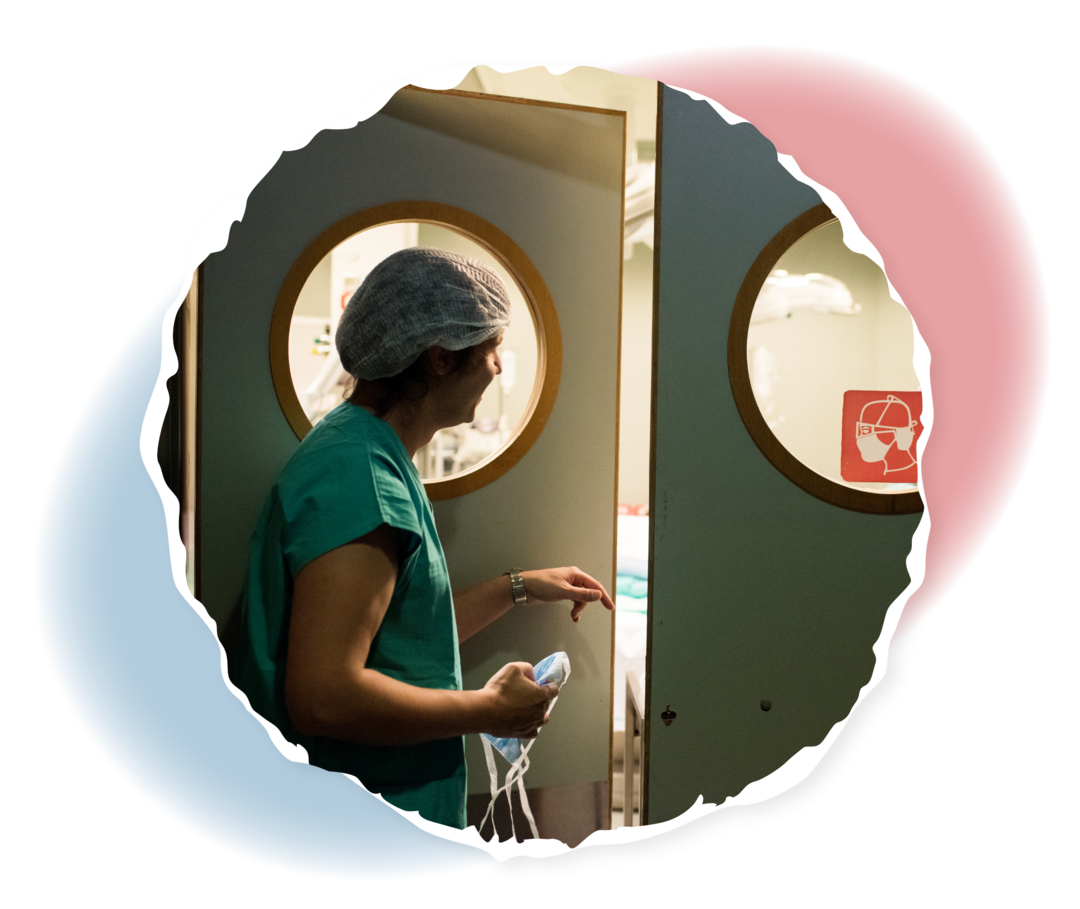 Eine Frau in medizinischer OP-Kleidung öffnet die Tür zu einem OP-Zimmer.