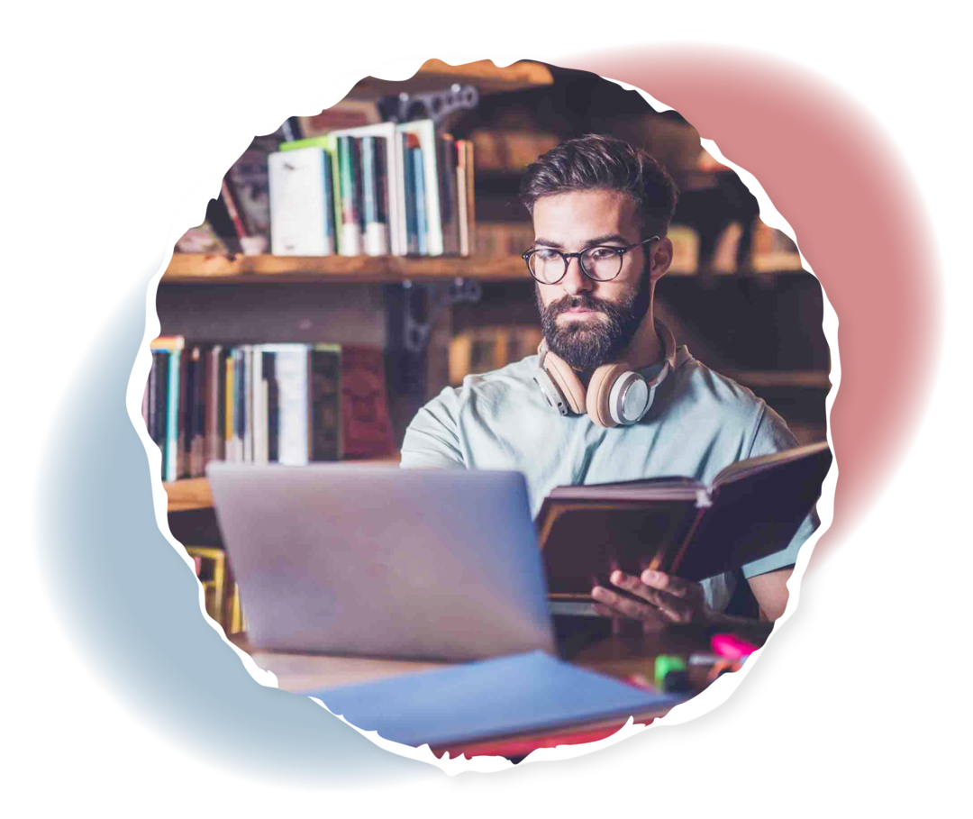 Informationsquellen Ein Mann sitzt vor einem Laptop und hält ein Buch in der Hand.