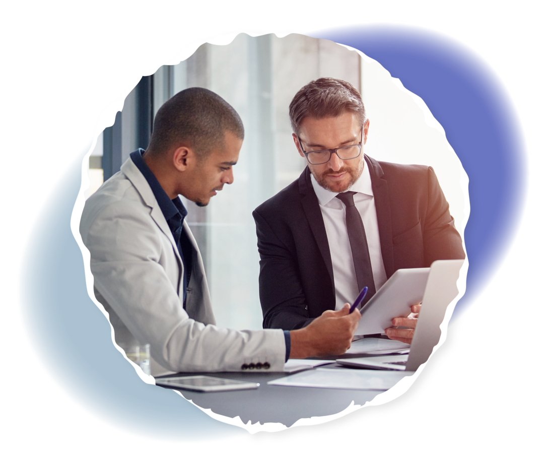 Zwei Männer sitzen an einem Schreibtisch und schauen gemeinsam auf Unterlagen.