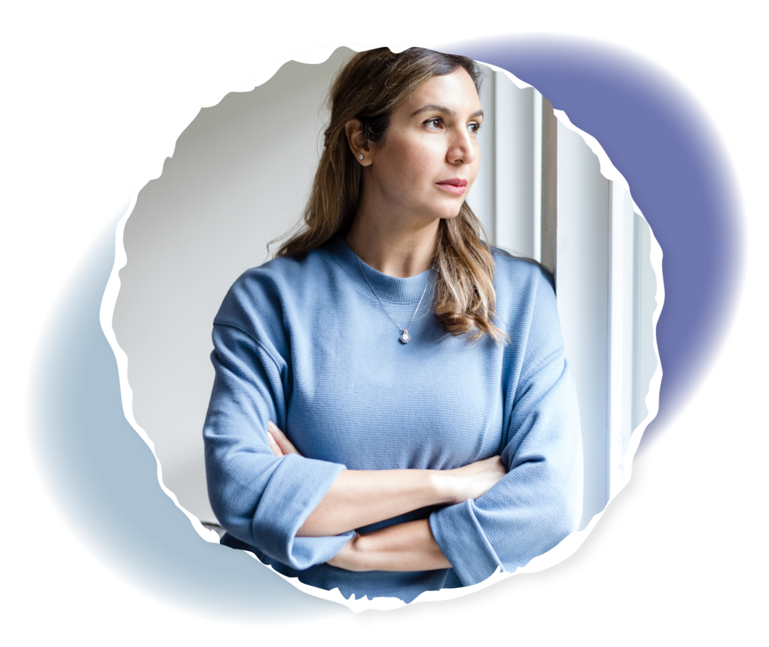 Eine Person steht mit verschränkten Armen vor einem Fenster. 