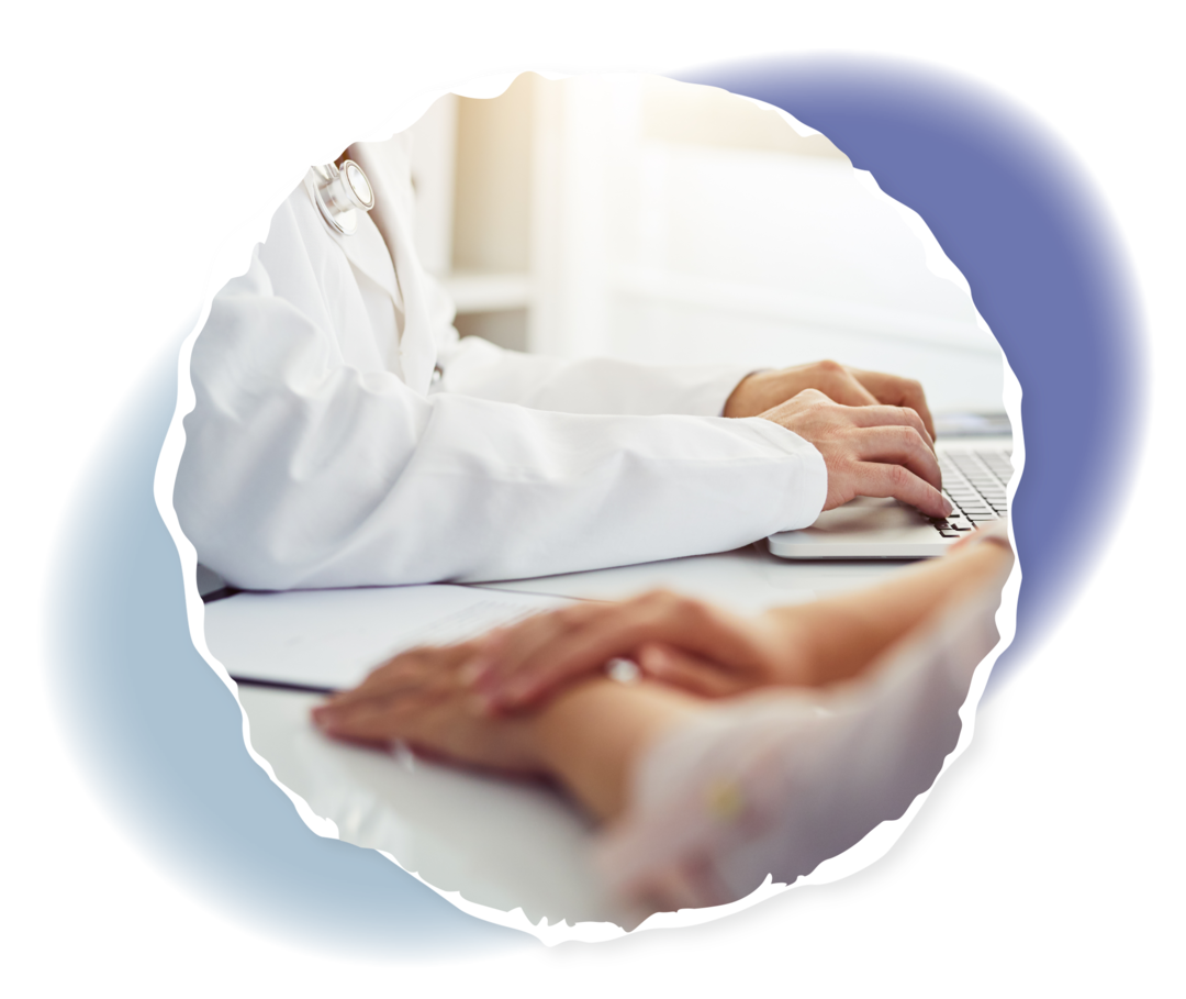 Fotoausschnitt: Zwei Personen sitzen an einem Tisch, die Arme sind dabei sichtbar. Eine Person trägt einen weißen Kittel und hat ein Stethoskop um die Schultern liegen. 