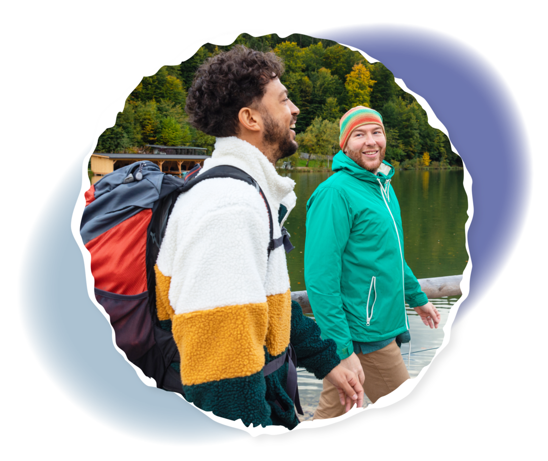 Zwei Personen gehen an einem Gewässer entlang und lächeln. 