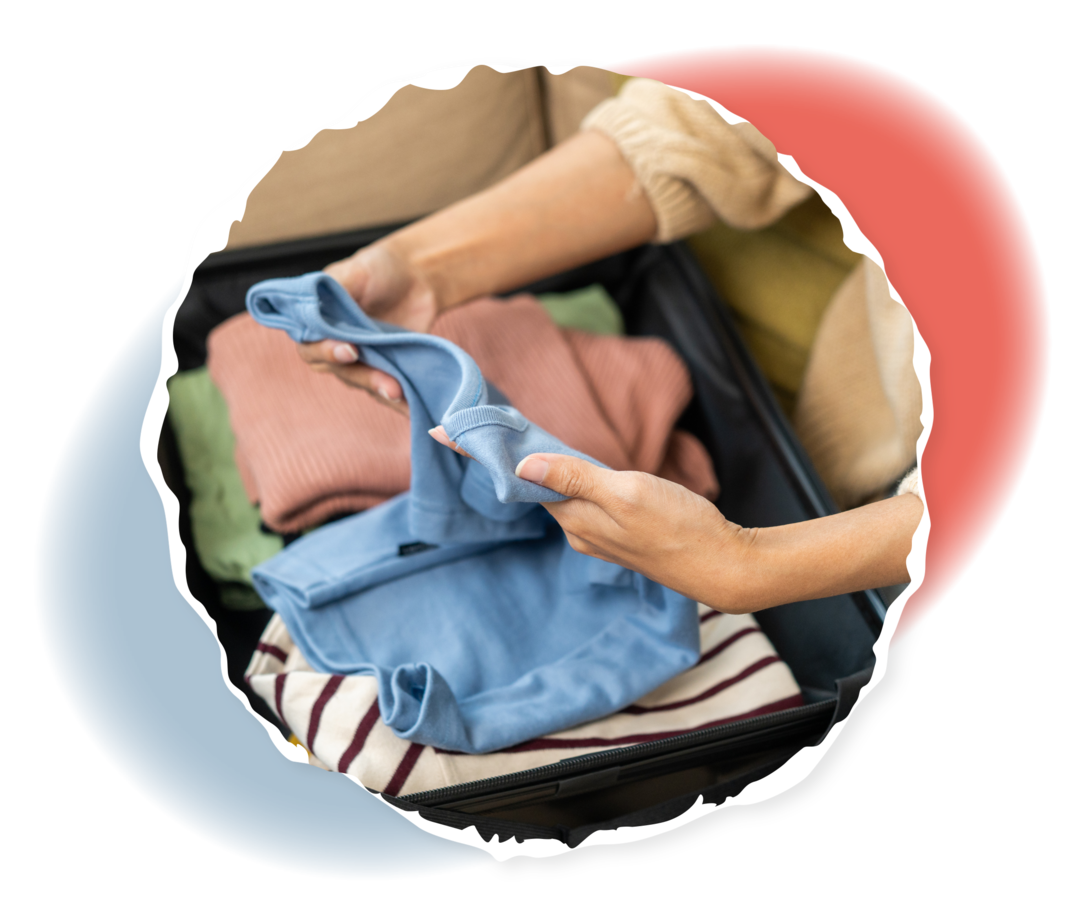 Eine Frau packt Kleidungsstücke in einen Koffer.