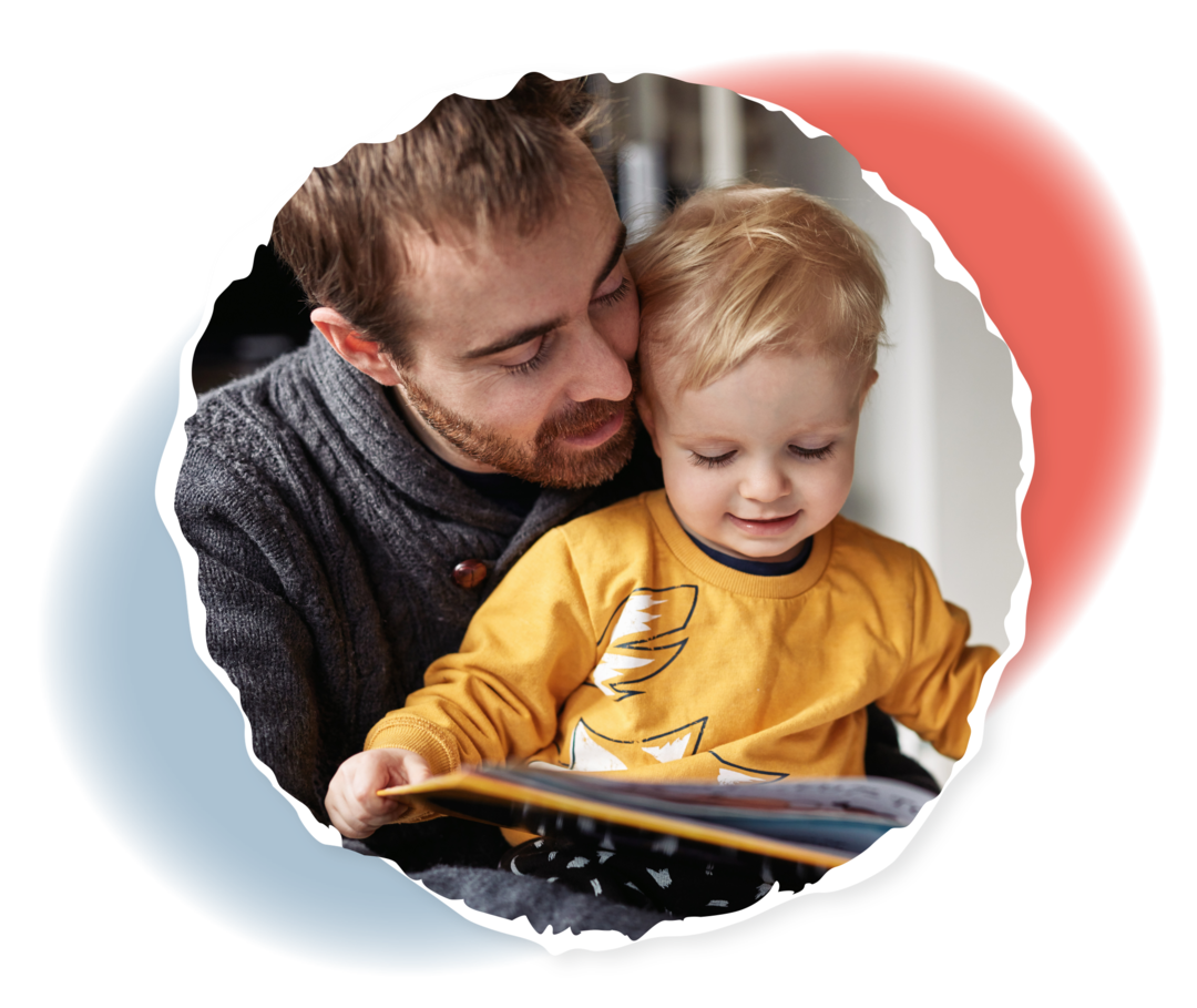 Ein junges Kind sitzt auf dem Schoß eines Mannes. Beide schauen auf ein aufgeschlagenes Bilderbuch in den Händen des Mannes.