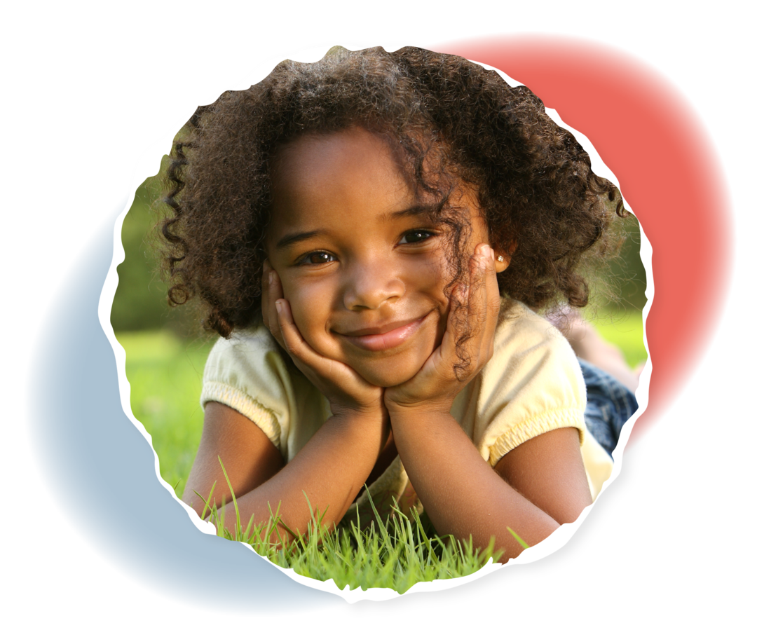 Ein junges Mädchen liegt auf einer Wiese und lächelt in die Kamera.