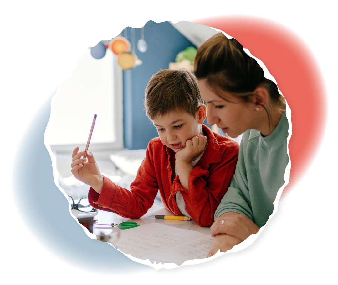 Ein Junge und eine Frau sitzen an einem Schreibtisch, auf dem sich verschiedene Unterlagen und Stifte befinden.