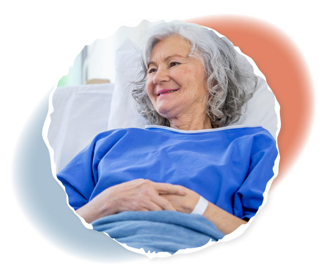 Eine ältere Person erhält eine Infusion und lächelt.  