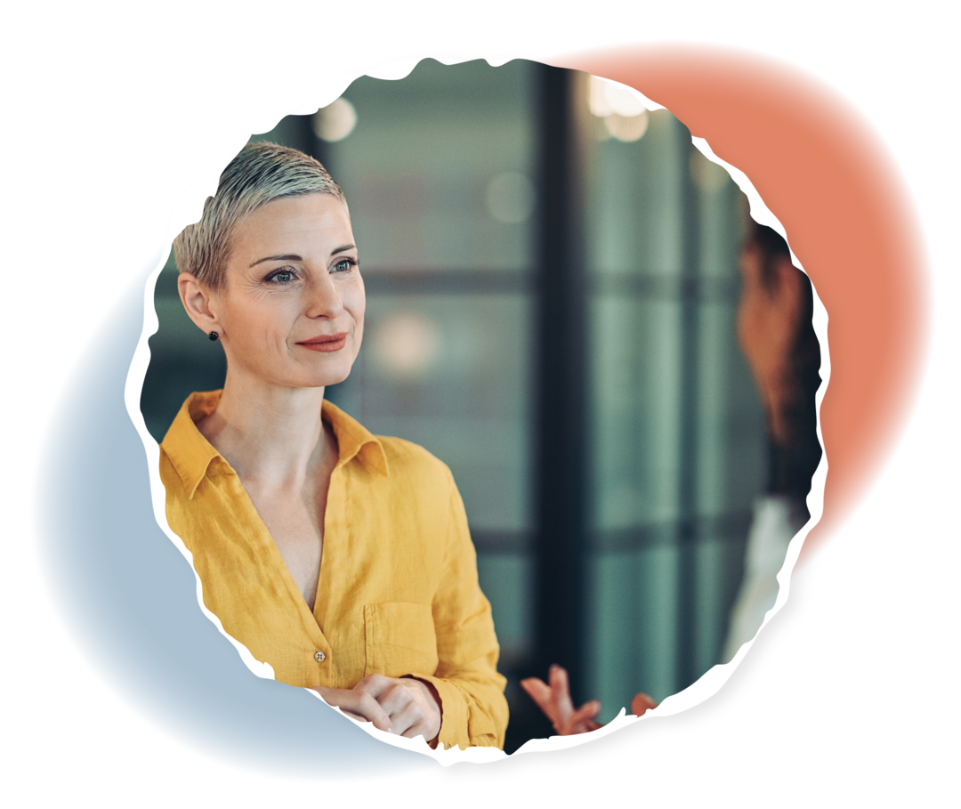 Zwei Frauen stehen sich bei einem Gespräch gegenüber: Die eine Frau ist von hinten zu sehen und spricht, die andere Frau ist von vorn zu sehen und hört zu.  