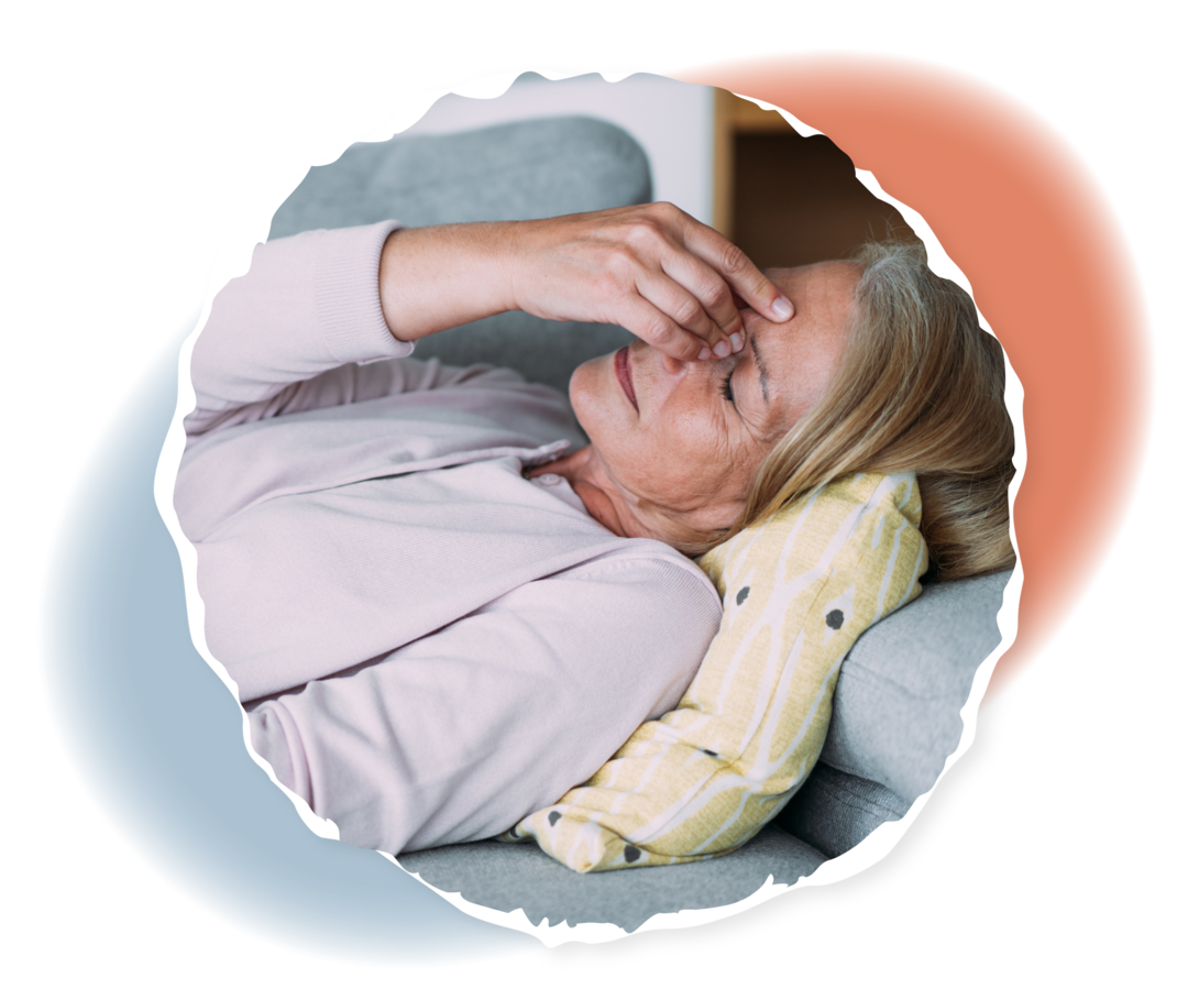 Eine Person liegt auf dem Sofa und fasst sich mit einer Hand an die Nasenwurzel. 