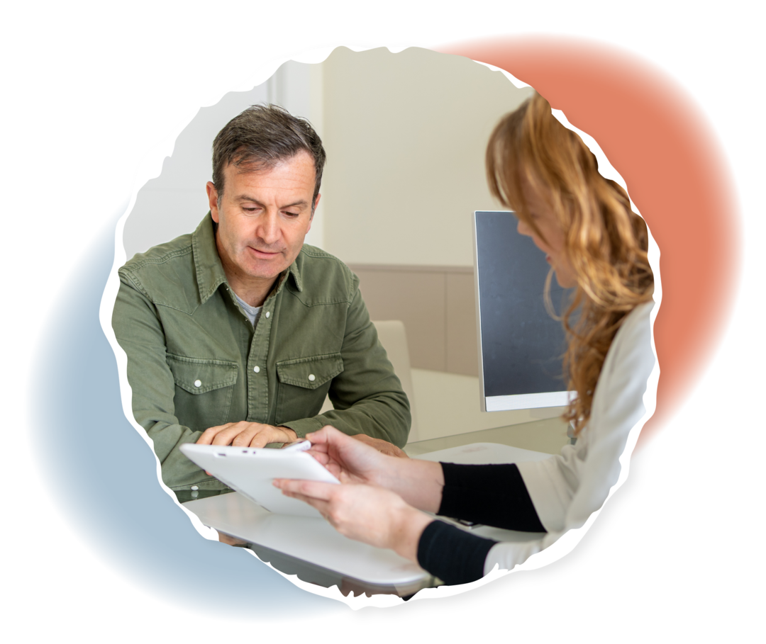 Eine Ärztin zeigt einem Mann etwas auf einem Tablet-Computer. 