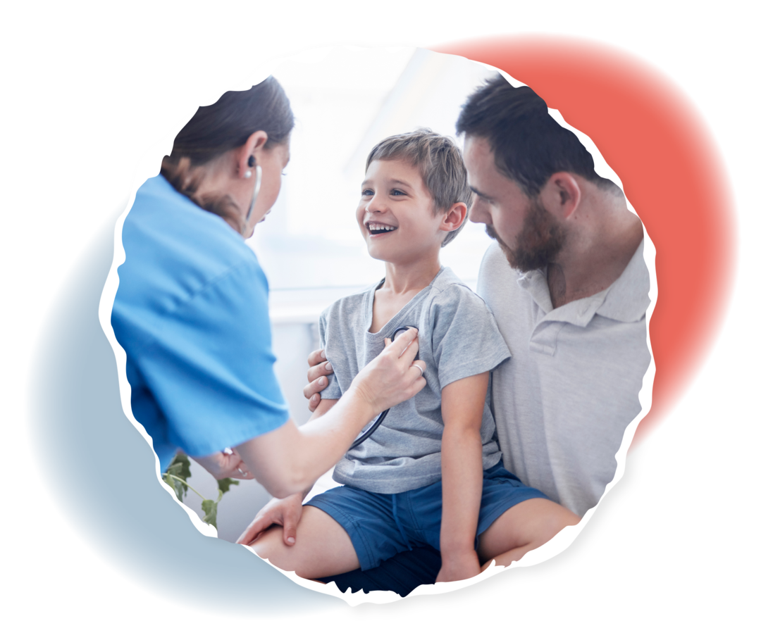 Ein Junge sitzt auf dem Schoß eines Mannes und wird von einer Ärztin mit einem Stethoskop untersucht. 