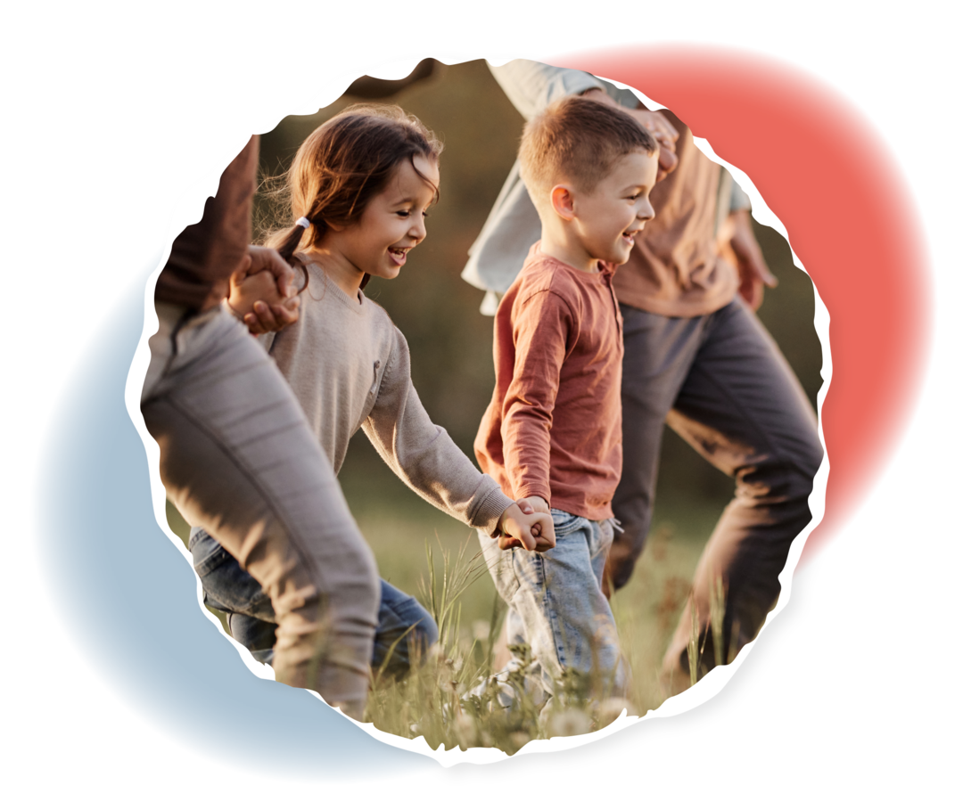 Zwei kleine Kinder und zwei Erwachsene halten sich an den Händen und laufen über eine Wiese. 