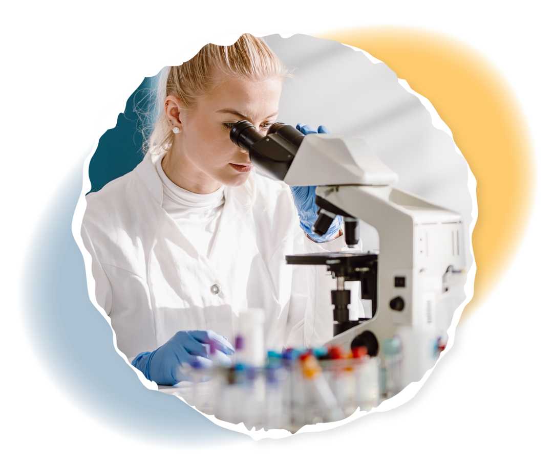 Myelofibrose: Blutuntersuchungen Eine Frau im weißen Kittel schaut durch ein Mikroskop.