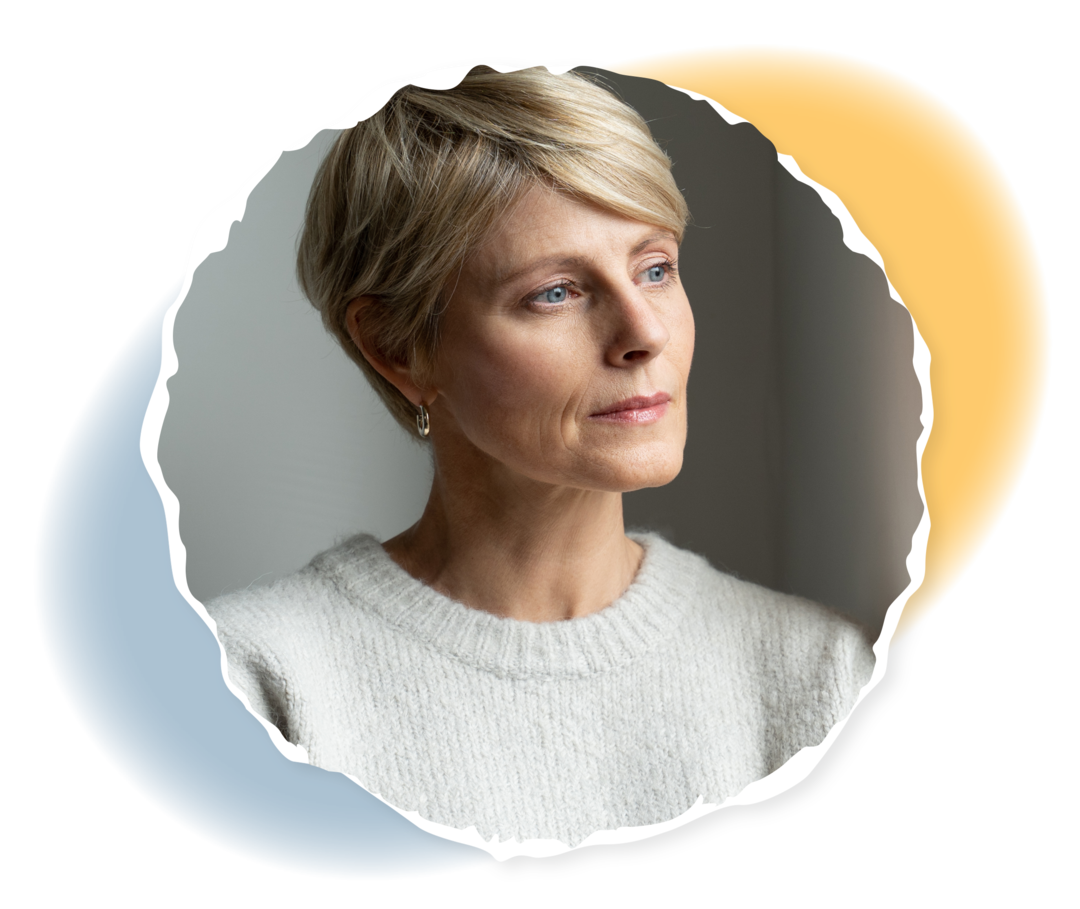 Eine Frau schaut nachdenklich aus dem Fenster.