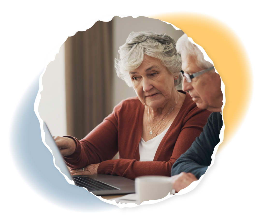 Zwei ältere Menschen schauen auf einen Laptop.